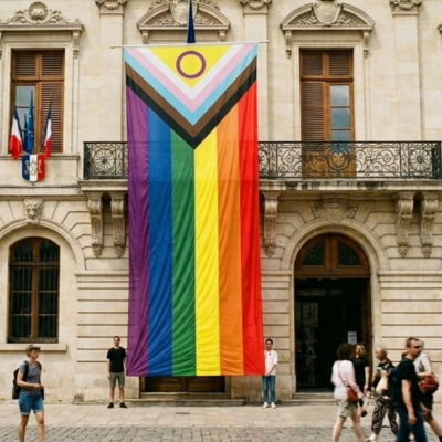 Drapeau géant Progress Pride 450x150cm suspendu sur la façade d'une mairie, symbole d'inclusion et de fierté